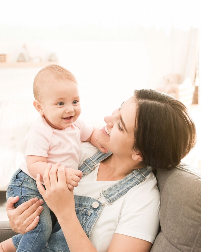 Mutter in Latzhose mit Baby auf Arm