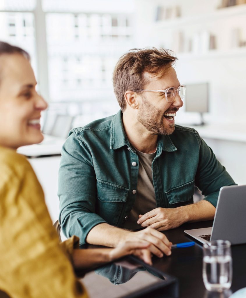 Junges Team sitzt zusammen am Schreibtisch vor Laptop